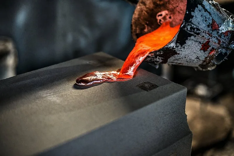 Sandguss — flüssiges Metall wird in die Sandform abgegossen